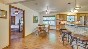 A spacious kitchen with wooden cabinets, a dining area with a table and chairs, and a bar with stools. - Dog-friendly Wills Point Home w/ Grill on 10 Acres (Wills Point)