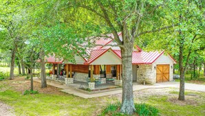 A lodge with a red roof, stone exterior, and a covered porch with outdoor seating. - Dog-friendly Wills Point Home w/ Grill on 10 Acres (Wills Point)