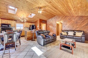 A spacious living area with a dining table, a leather sofa, and a glass coffee table. - Pocono Vacation Rental With Game Room! (Tobyhanna)