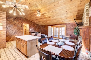 A cozy cabin with a wooden interior, a dining area with a large table and chairs, and a ceiling fan with lights.