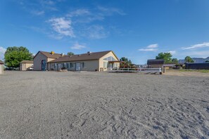 A residential property with a large gravel driveway, a house with a garage, and a fenced yard.