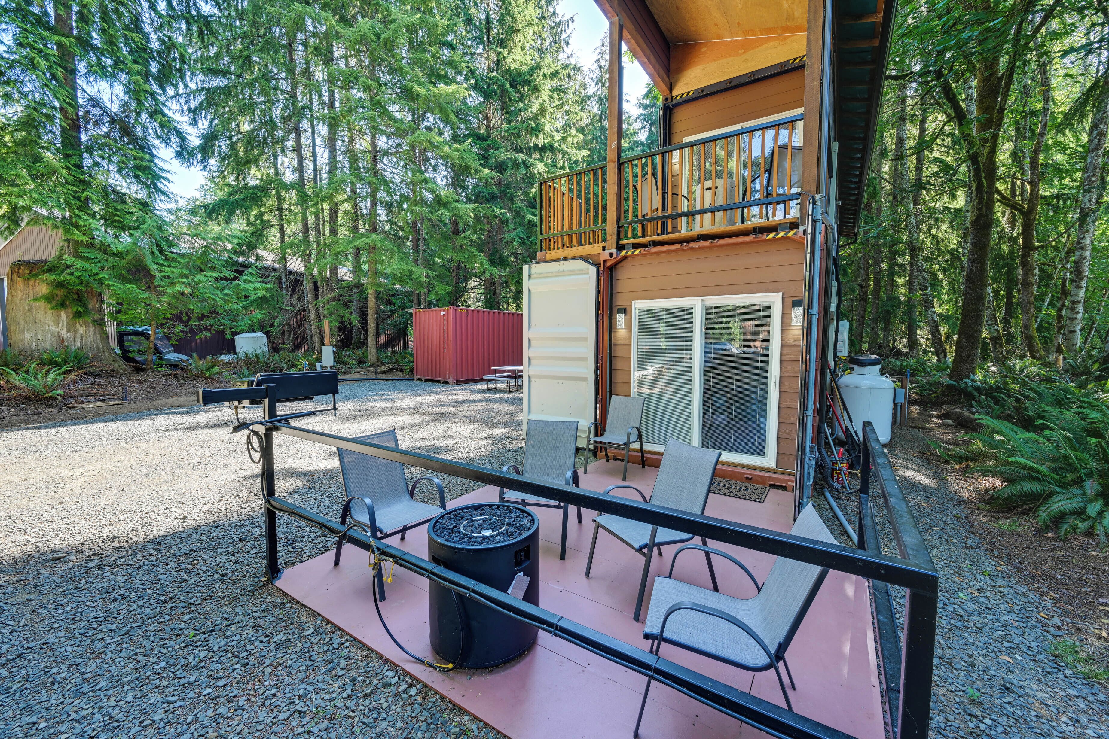 Une cabane dotée d’une terrasse, de meubles de jardin et d’un foyer extérieur.