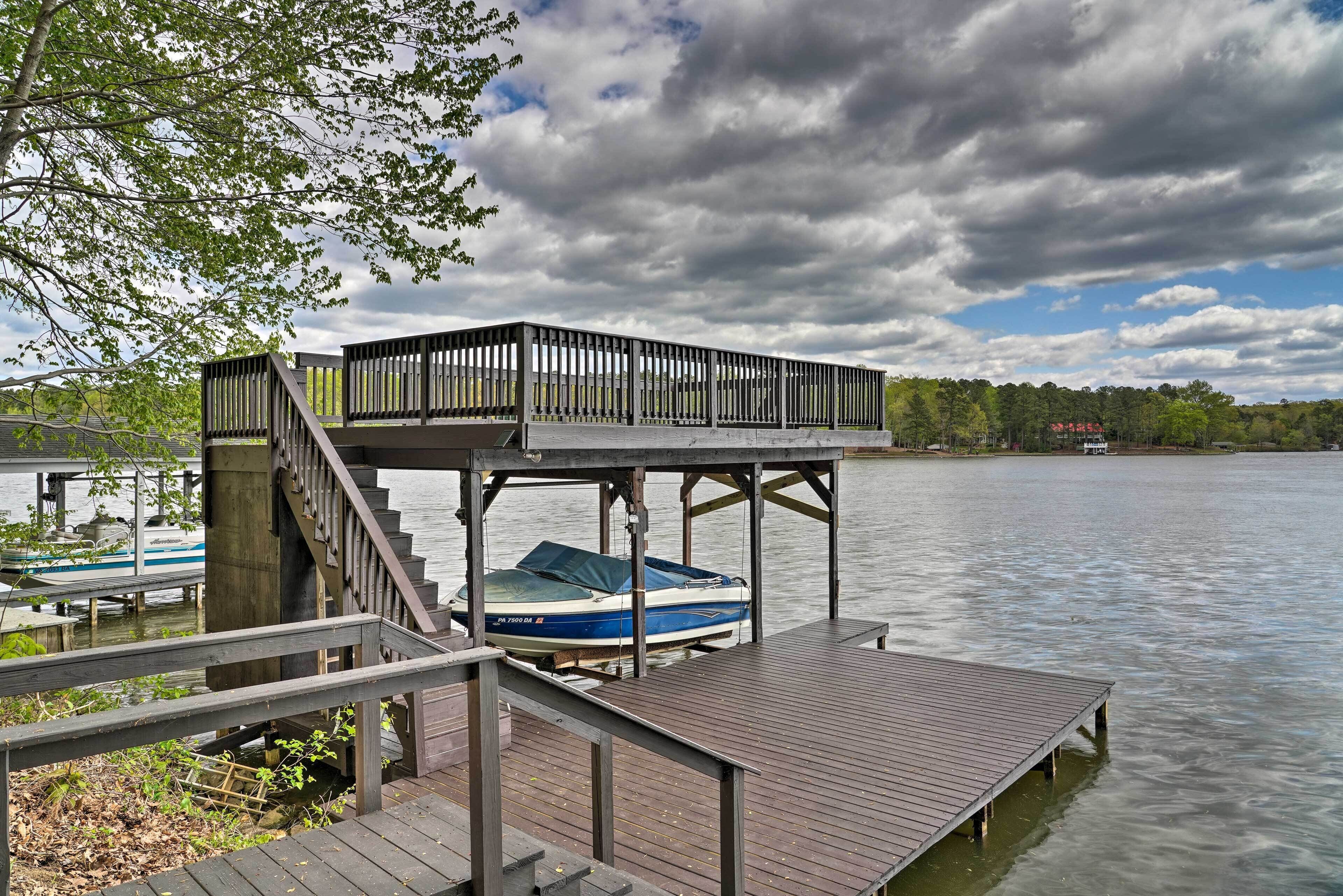 A wooden dock with a covered seating area and a boat docked underneath.