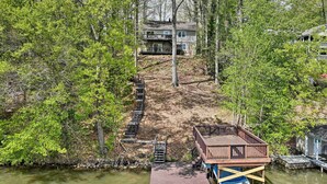 Een huis met een steiger die in een rivier uitstelt, omringd door dichte bomen.