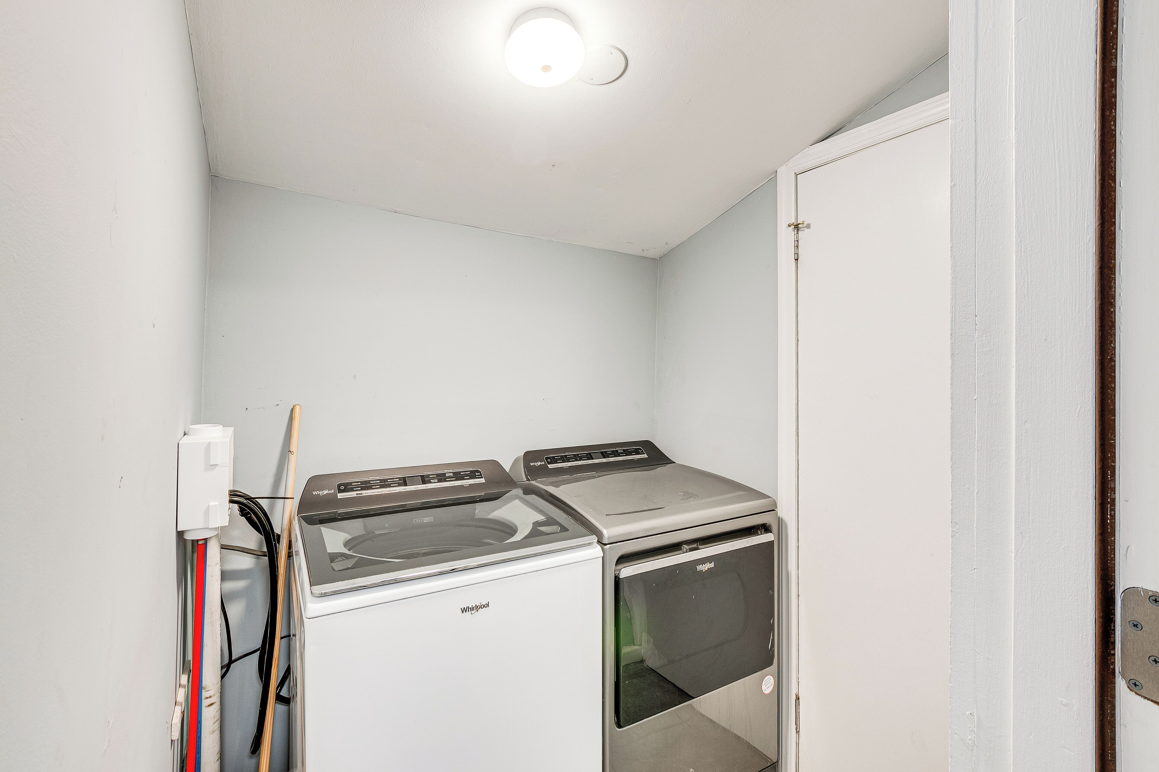 Une buanderie équipée de deux machines à laver et deux sèche-linge superposés, avec un mur blanc et une porte.