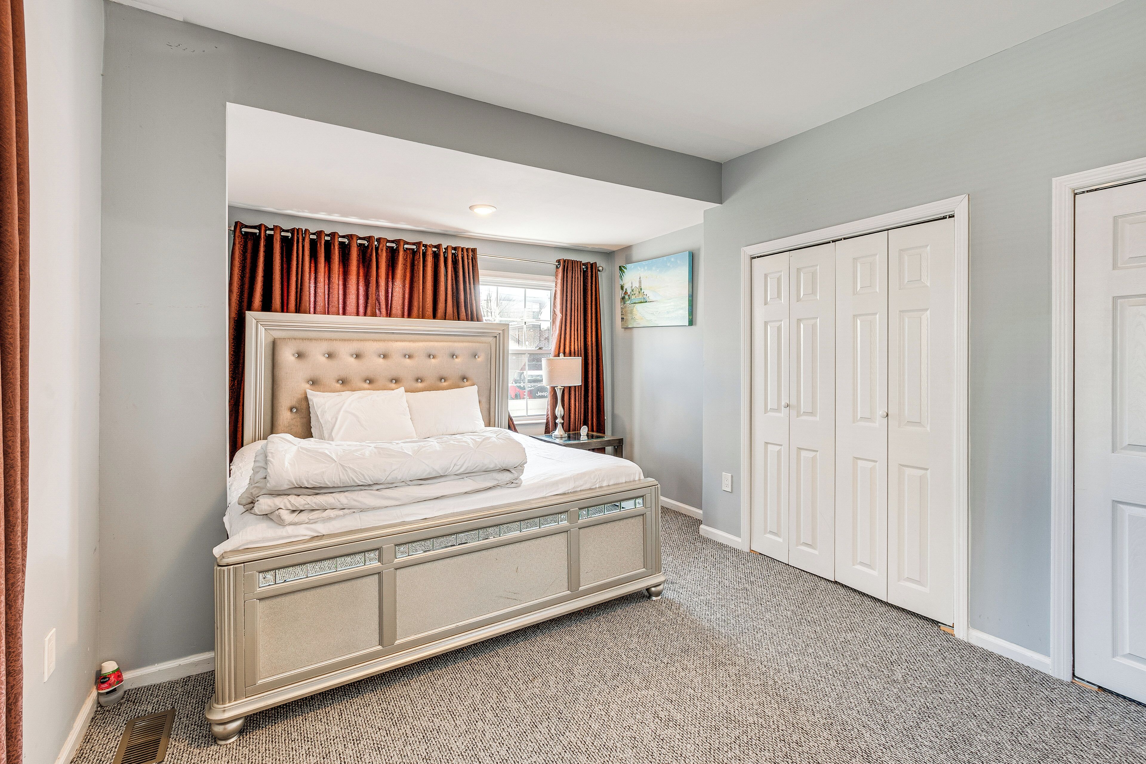A bedroom with a large bed, a nightstand, a lamp, and a closet.