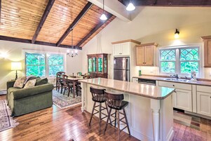 Una cocina amplia con techo de madera, una isla central con taburetes y un refrigerador.