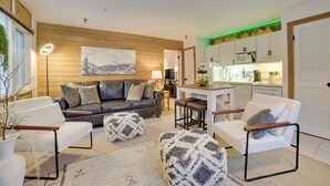 Ein modernes Wohnzimmer mit einer Ledersofa, weißen Sesseln und einer Essecke mit Hocker.