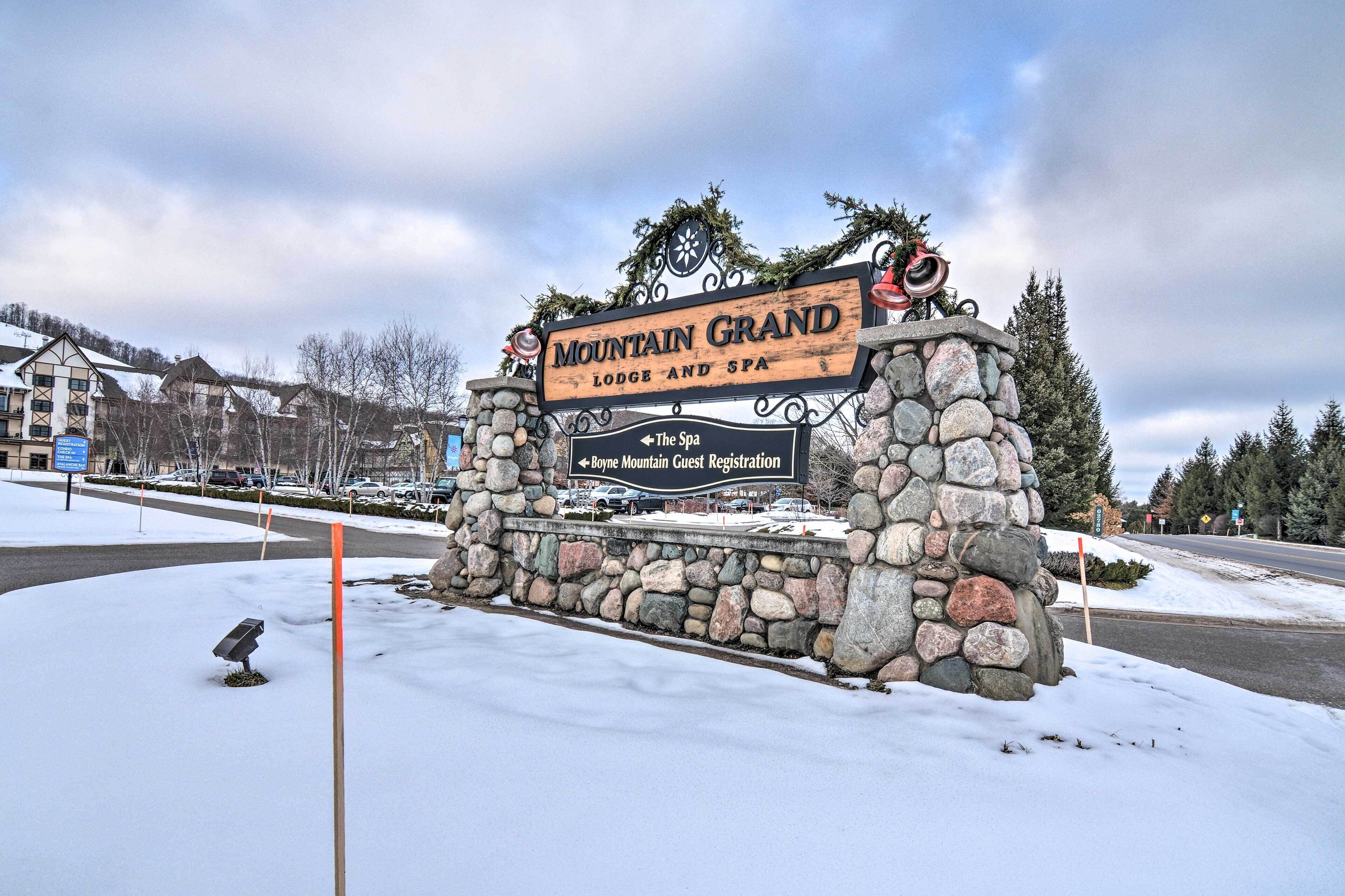 A stone sign for Mountain Grand Lodge and Spa with directional arrows to guest registration and the spa.