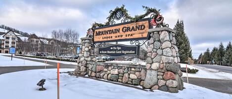 A stone sign for Mountain Grand Lodge and Spa with directional arrows to guest registration and the spa.