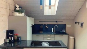 Une cuisine compacte avec un îlot central, un luminaire suspendu et une petite fenêtre.