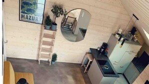 Un intérieur moderne et compact, avec un plancher en bois, un canapé, une table à manger et un coin cuisine.