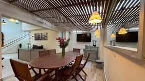 A modern dining area with a wooden table and chairs, a vase with flowers, and pendant lights. - Hotel 12 Nights (Medellín)
