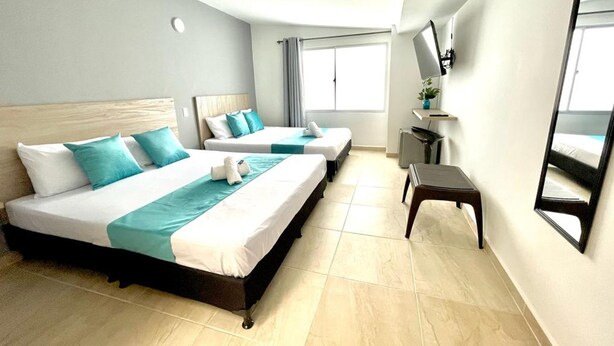A hotel room with two beds, a TV, a small table, and a window with curtains. - Hotel 12 Nights (Medellín)