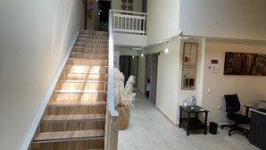 A staircase leading to a second floor, a reception desk, and a painting on the wall. - Hotel 12 Nights (Medellín)