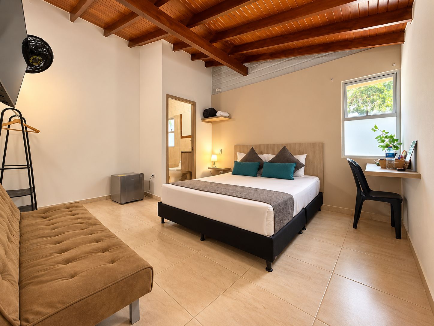 Un dormitorio con cama, mesita de noche, lámpara y ventana.