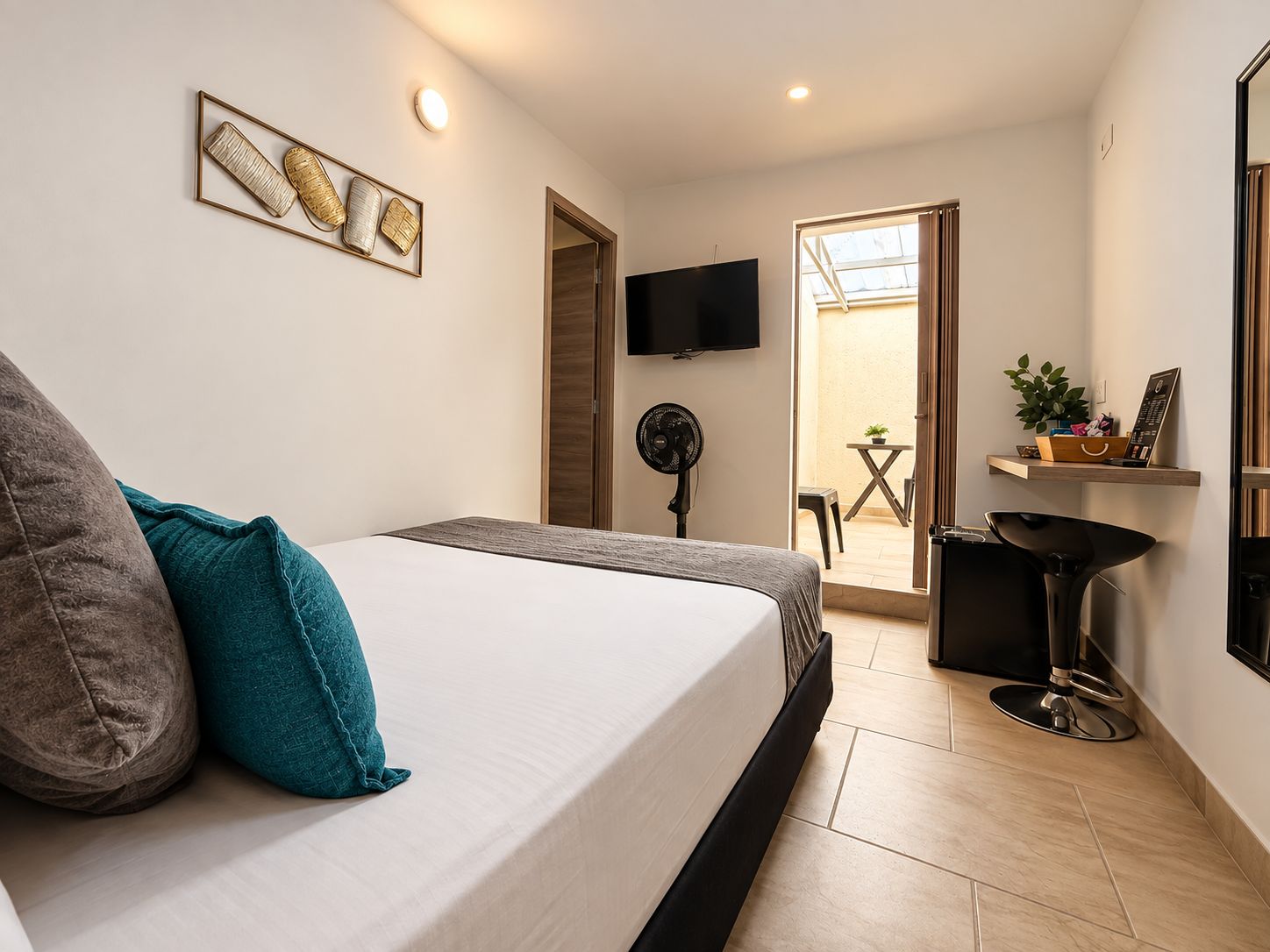 Un dormitorio con una cama, un televisor, un ventilador y vistas a un espacio exterior.