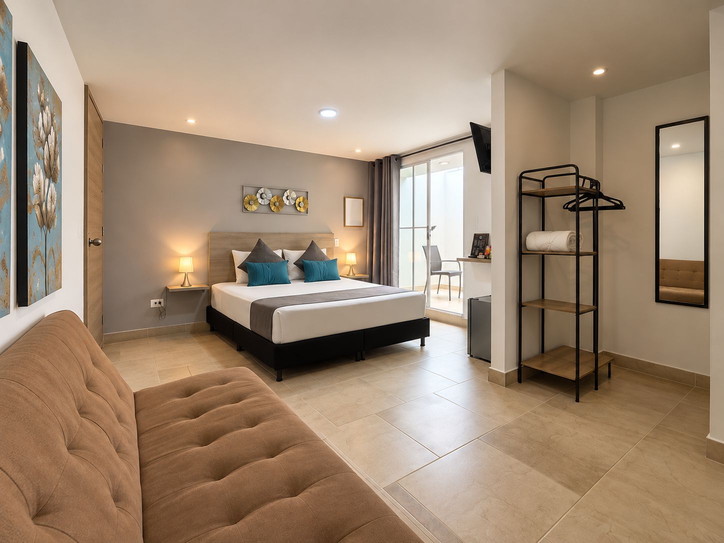 Quarto de hotel moderno com cama, mesas de cabeceira, sofá, escrivaninha e guarda-roupa.