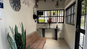 A room with a sofa, a table with a vase, and a clock on the wall. - Hotel 12 Nights (Medellín)