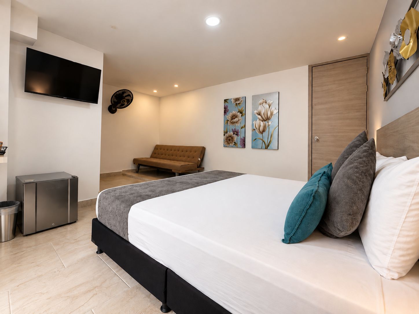 Quarto com cama, sofá, televisão e obras de arte na parede.