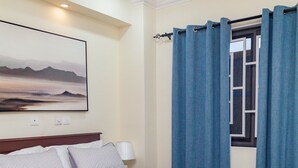 Un lit bien fait, avec une couette blanche, une tête de lit en bois et un tableau accroché au mur.