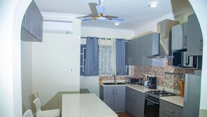Une cuisine de taille réduite avec un coin repas, un ventilateur de plafond et un four à micro-ondes.