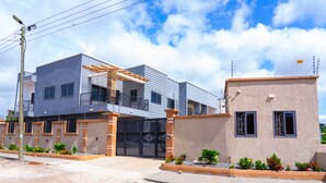 Une maison moderne à deux étages, dotée d’un balcon, d’un garage et d’une petite dépendance attenante.