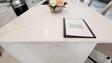 A modern kitchen with white cabinetry, a stainless steel oven, and a dining area with a white table and chairs.