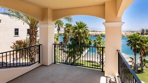 A balcony with a view of a beach and palm trees.