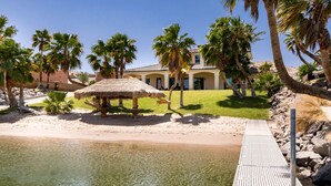 A resort with a pool, palm trees, and a thatched-roof hut.