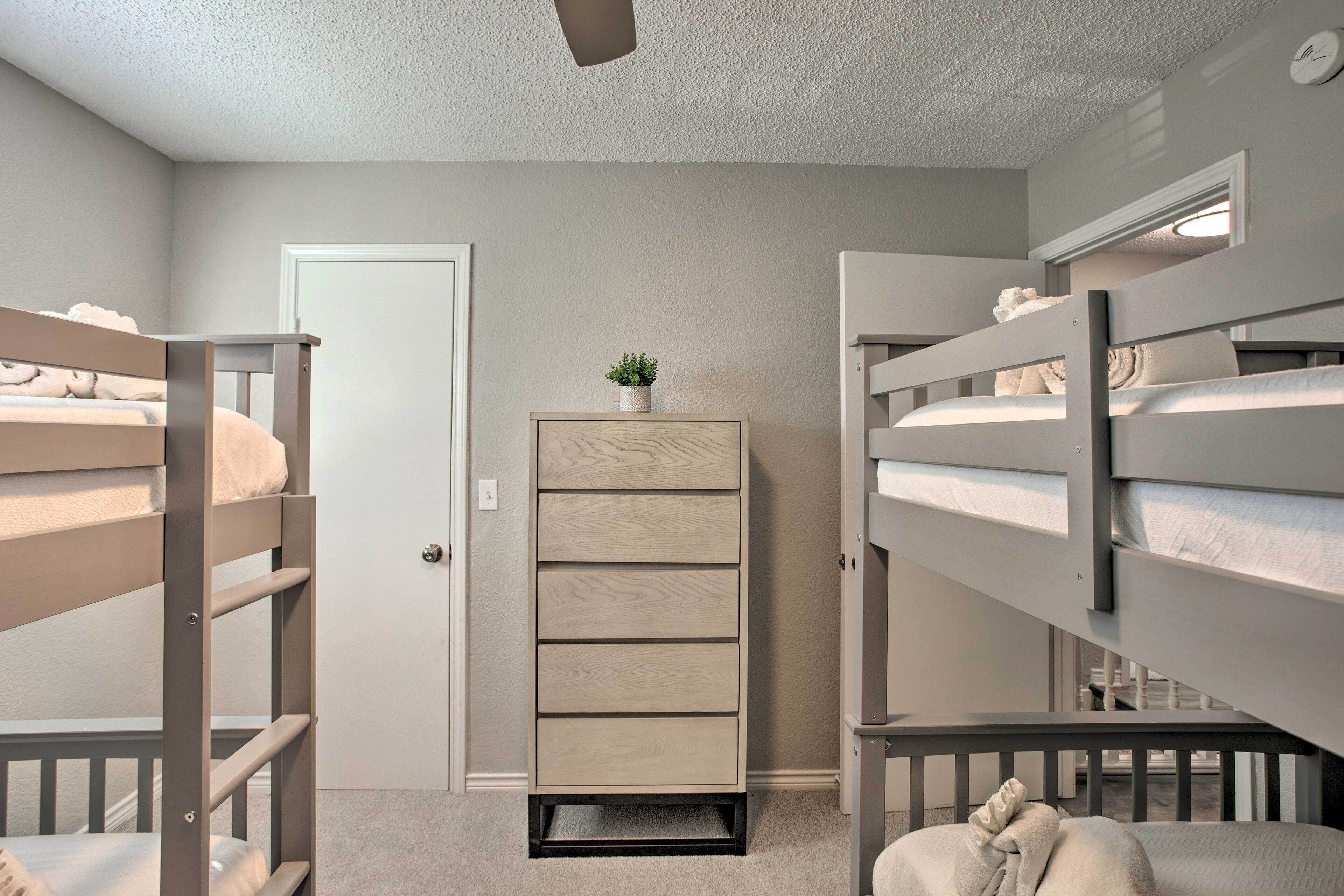 Une chambre avec un lit superposé, une commode en bois et une petite plante.