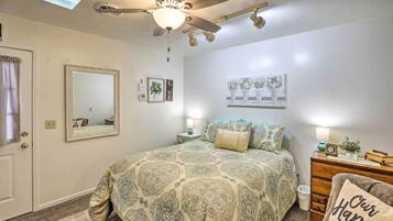 A bedroom with a bed, a ceiling fan, a dresser, a mirror, and wall decorations.