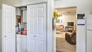 A compact living space with a white door, a laundry area, a sofa, and a TV in the background. - Akron Apartment w/ Balcony - Hunting Nearby! (Akron)