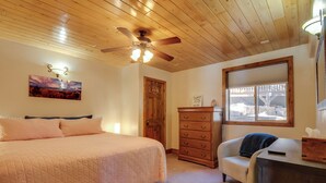 A bedroom with a bed, a dresser, a chair, a ceiling fan, a window, and a door. - The Bridgeway Casita - Apt Near Natl Parks (Duck Creek Village)