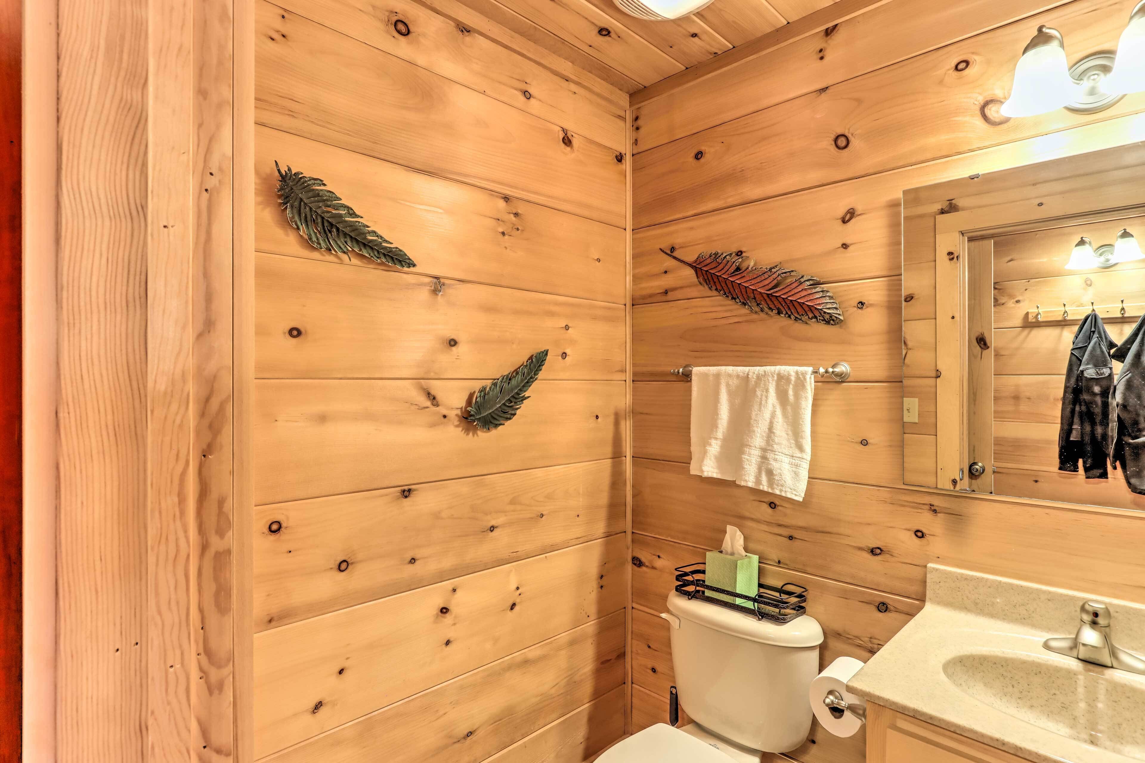 A wooden-paneled bathroom with a toilet, sink, and mirror.