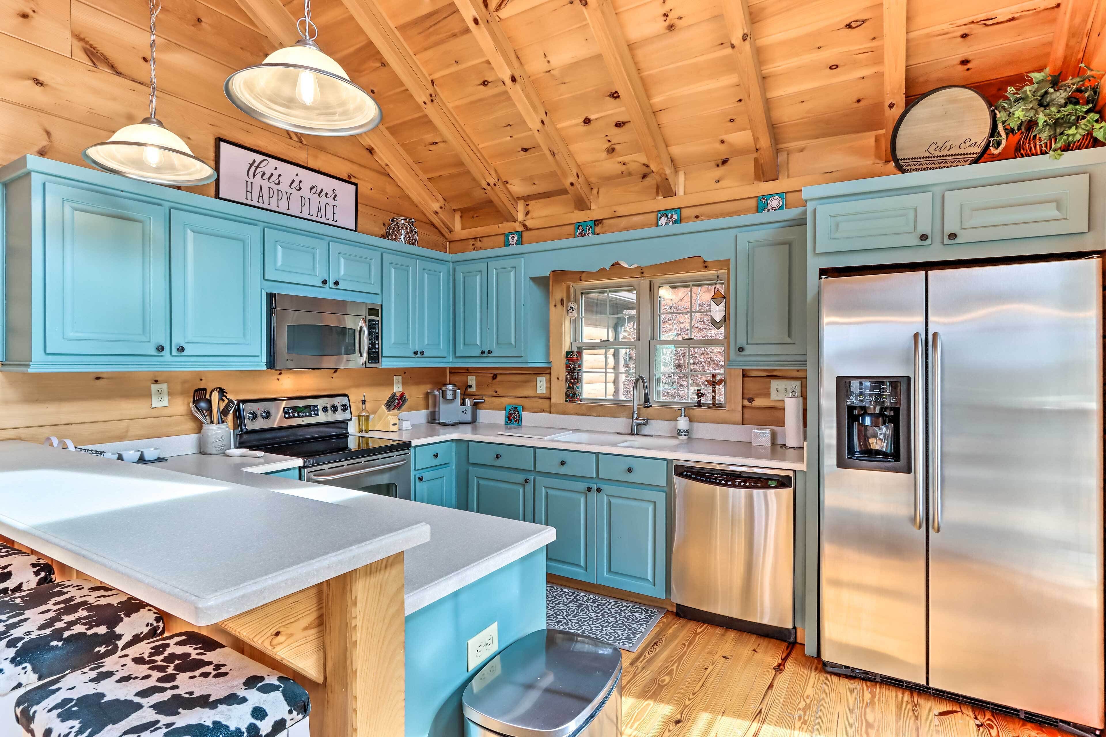 A kitchen with light blue cabinets, stainless steel appliances, and a wooden ceiling.