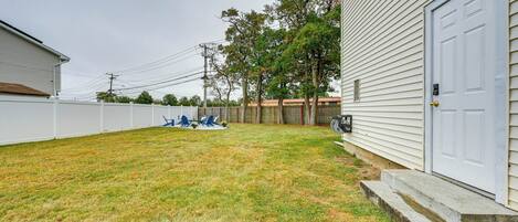 A residential backyard with a white fence, a lawn, and a garage.