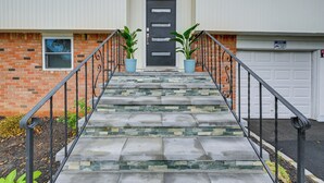 A two-story house with a front door, a garage, and a staircase leading to the front door. - Bay Shore Vacation Rental ~ 7 Mi to the Beach (Bay Shore)