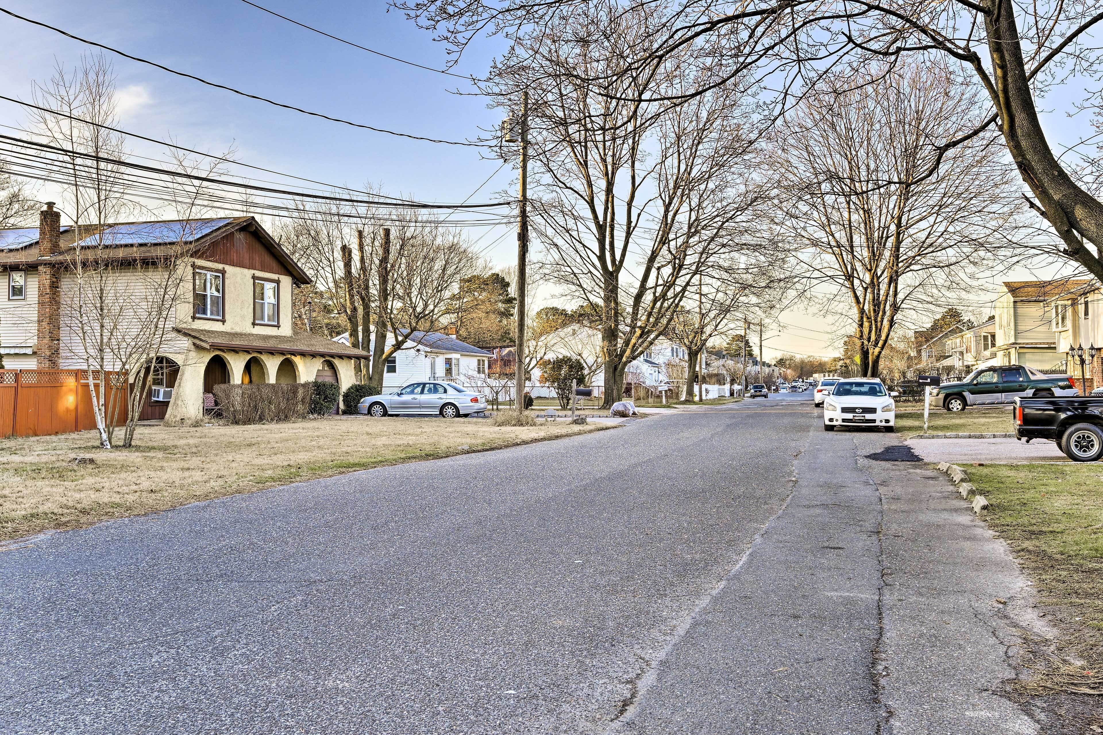 A residential street with houses, parked cars, and bare trees.