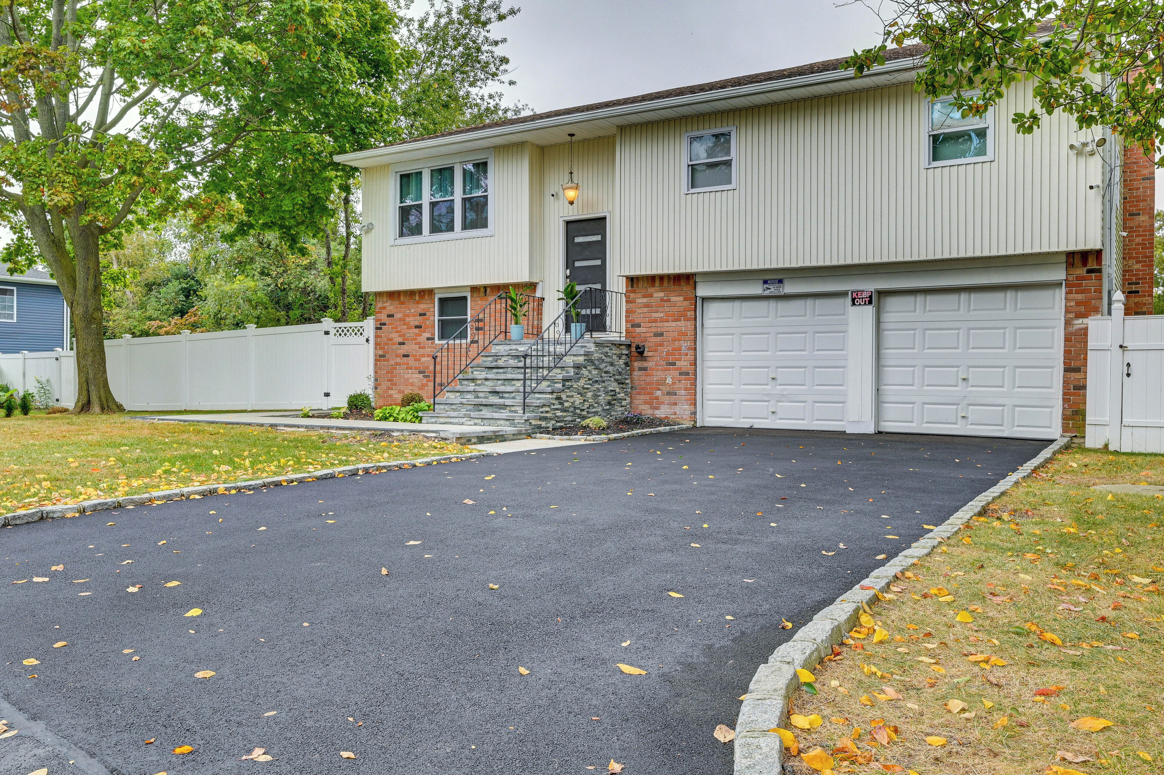 A two-story house with a garage, a front porch, and a driveway with fallen leaves.