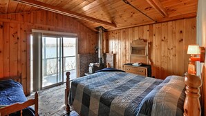 Une chambre dans une cabane en bois, avec un grand lit, une fenêtre et une cheminée.