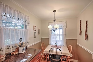 A dining area with a table, chairs, a chandelier, and a window with curtains. - Bayfront Hancock Cottage w/ Beach Access & Views! (Hancock)