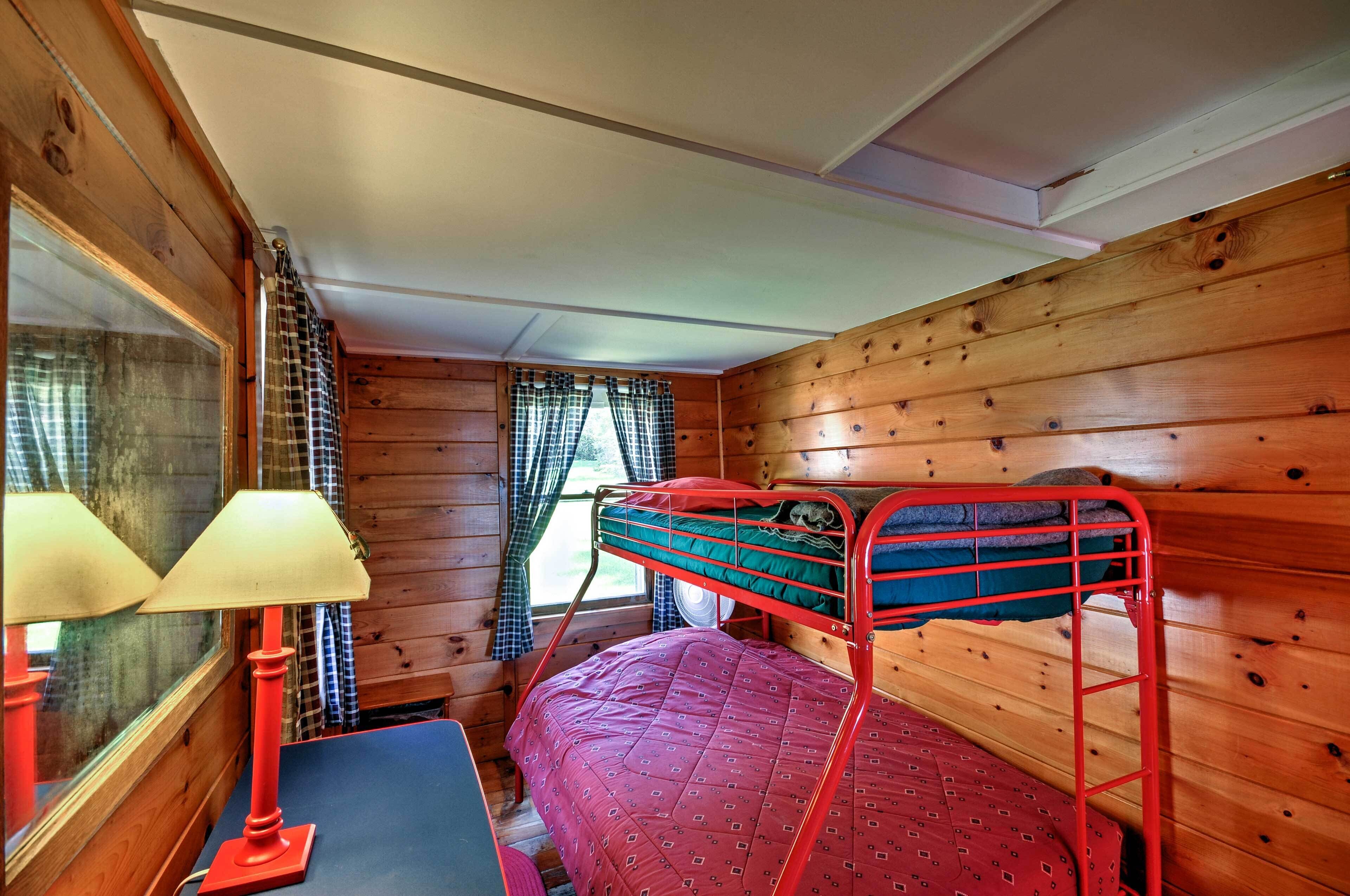 Une cabine équipée d’un lit superposé, d’un bureau avec une lampe et d’une fenêtre avec des rideaux.