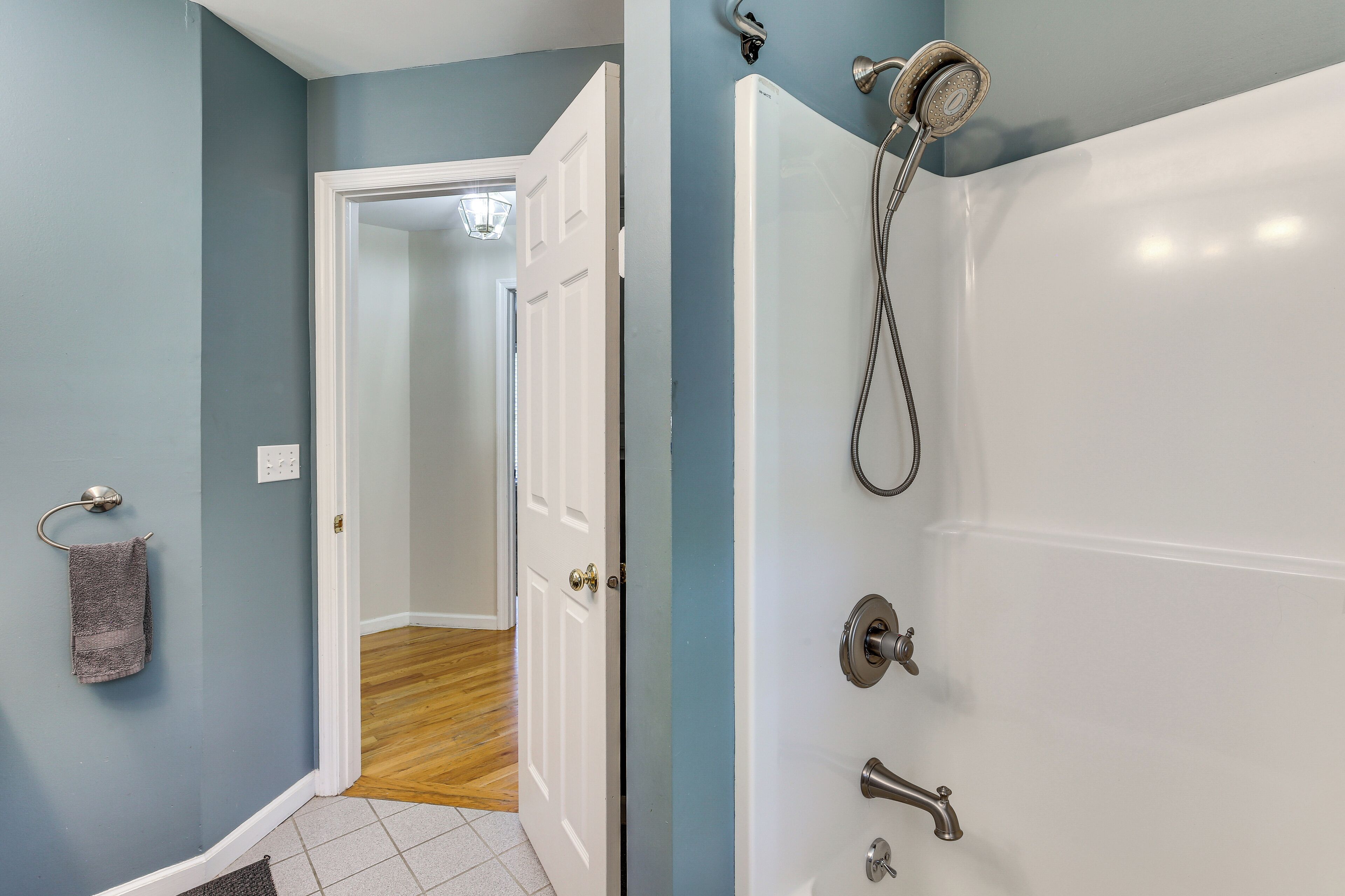 A bathroom with a bathtub, a showerhead, and a towel rack.
