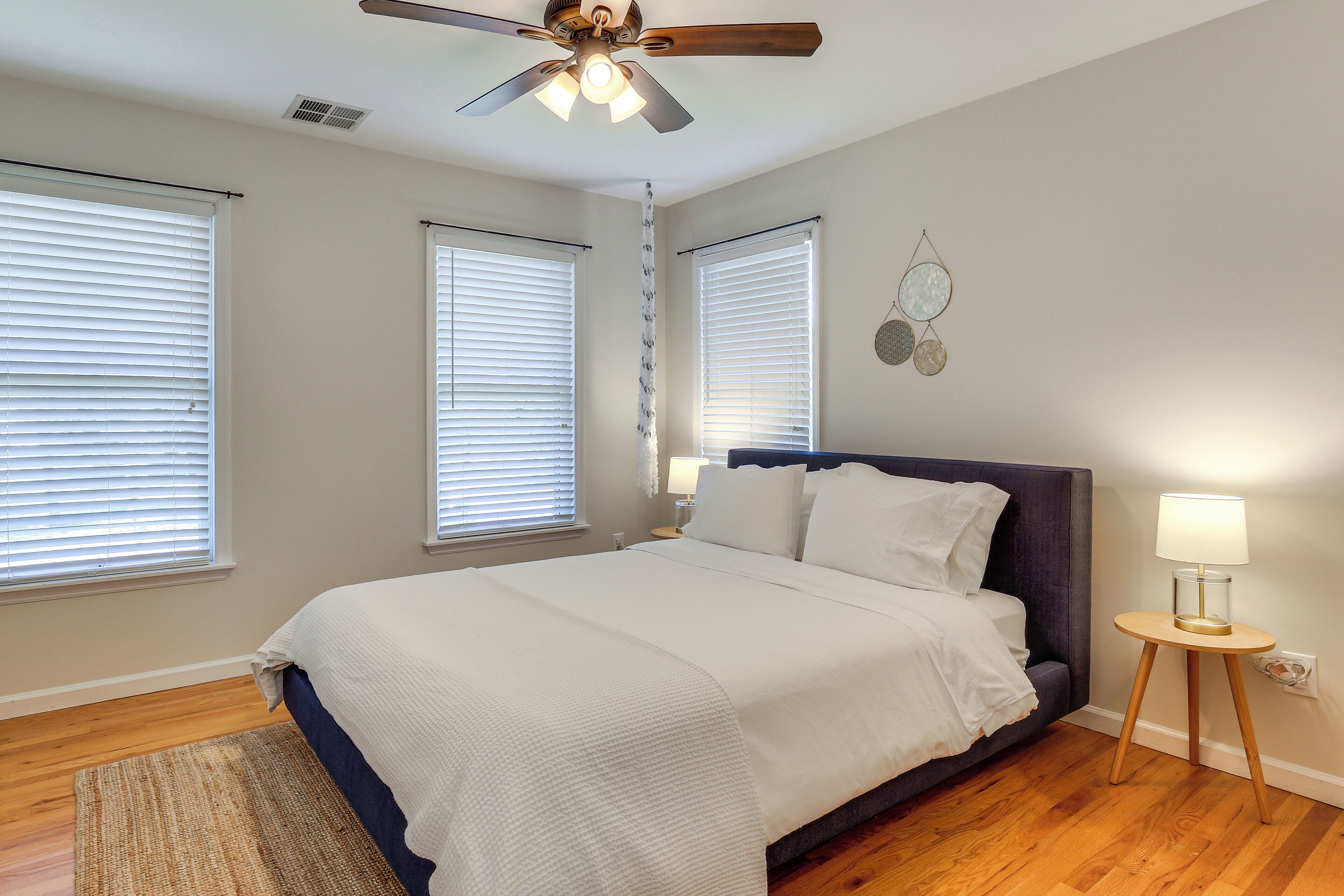 A bedroom with a bed, a ceiling fan, and a bedside table with a lamp.