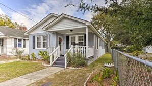 A single-story house with a front porch, a visible front door, and a small front yard with a fence and some plants.
