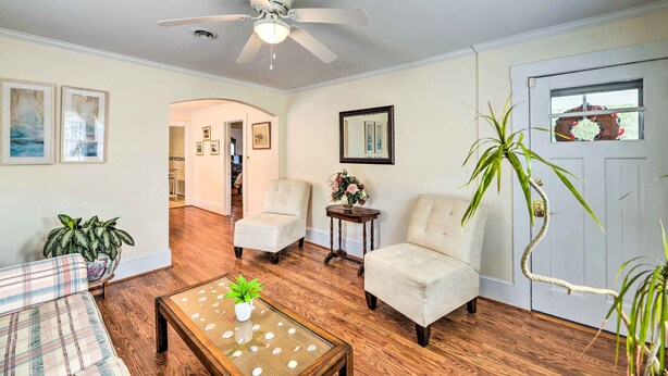 A living room with a ceiling fan, two armchairs, a coffee table with a plant, and a door with a wreath.