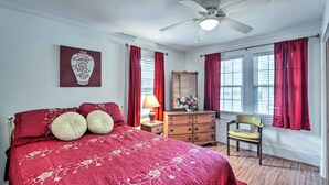 A bedroom with a large bed, a dresser, a chair, and a ceiling fan.