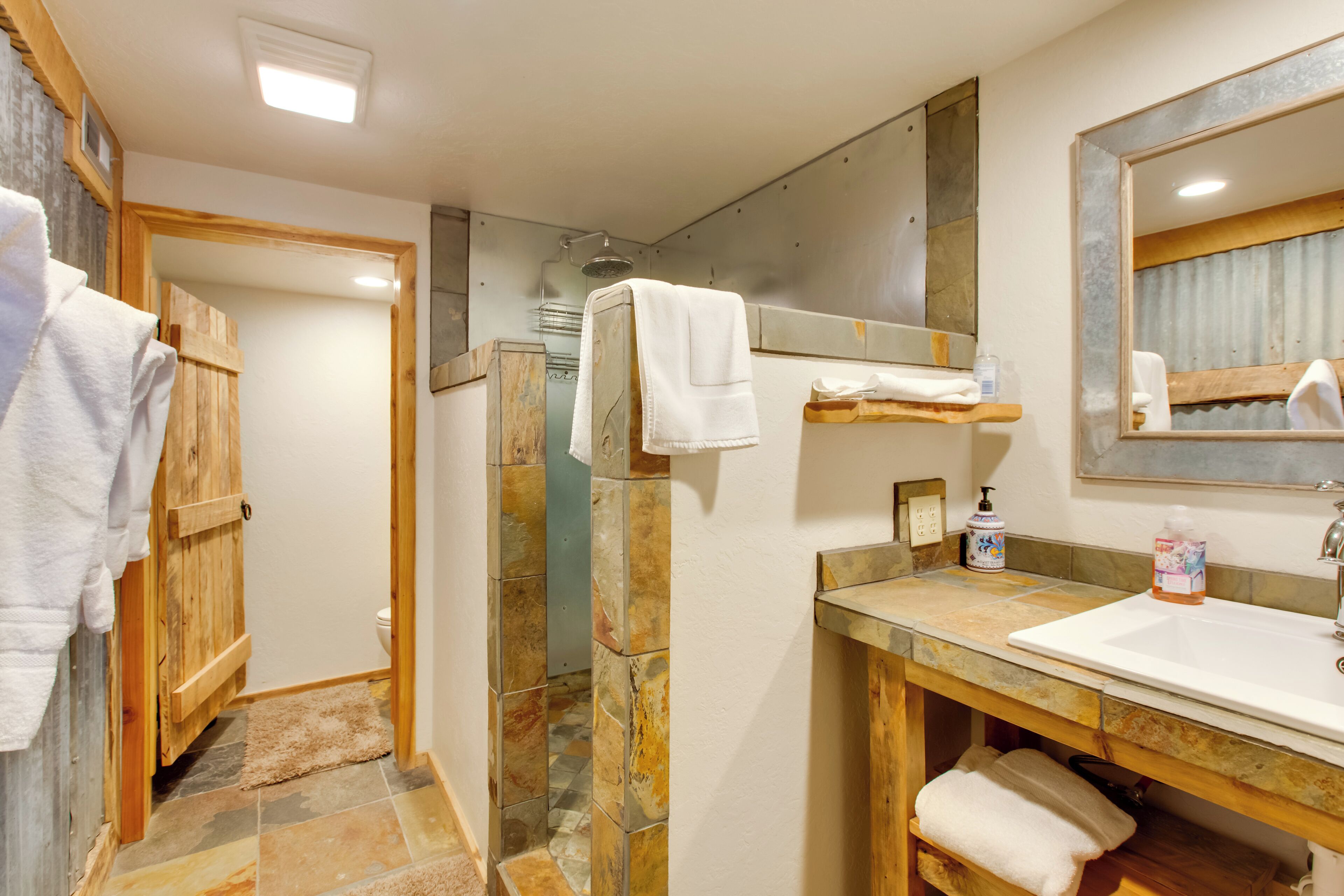 Un bagno con doccia, lavandino, specchio e asciugamani.