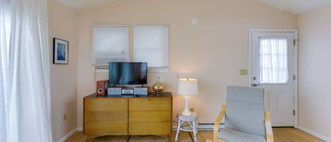 Ein Zimmer mit einem Holzkasten, einem Fernseher, einer Lampe und einem Stuhl.